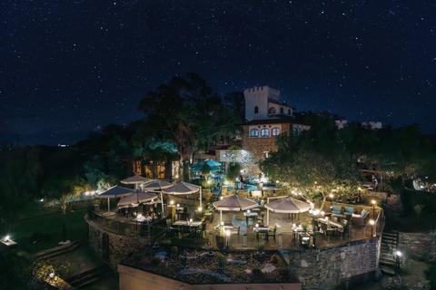 Hoch über dem Trubel der Stadt, eingebettet in die sanften Ausläufer des Khomas-Hochlands, lädt unsere Gartenterrasse zum Verweilen, Durchatmen und Genießen des Moments ein.
Von Sonnenaufgang bis Sonnenuntergang bietet diese Oase unter freiem Himmel einen Panoramablick über Windhoek, wo die roten Dächer der Hauptstadt auf die sanften, hügeligen Silhouetten der fernen Berge treffen. Das Khomas Hochland mit seinen schroffen Bergrücken und goldenen Farbtönen erstreckt sich bis zum Horizont — eine dramatische Kulisse, die sich je nach Lichteinfall verändert.
Den ganzen Tag über servieren wir frische saisonale Gerichte, handgemachte Kuchen aus unserer Konditorei und duftende Kaffeesorten. Wenn die Sonne untergeht, verwandelt sich die Terrasse — der Himmel erstrahlt in Farben — und es ist Zeit für einen klassischen Sundowner-Cocktail, der langsam getrunken wird, während sich die Welt goldgelb färbt.
Das ist Namibia von seiner ruhigsten — und spektakulärsten Seite.