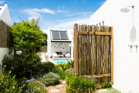 Indigener Garten, der den Pool und den Außenduschbereich umgibt, mit Weg vom Strand