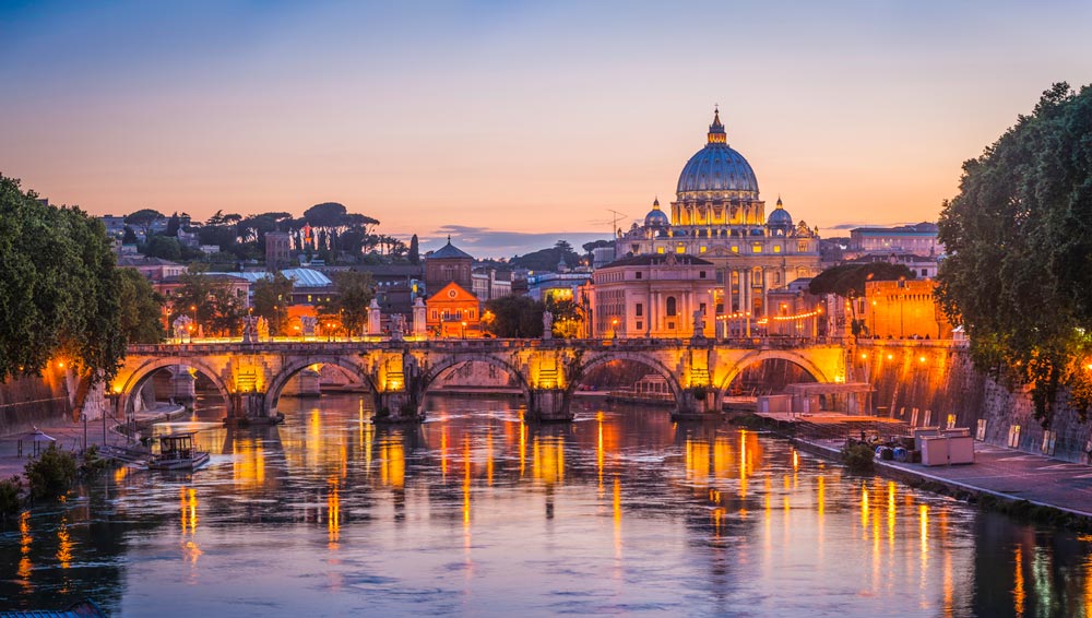 illuminated st. peters cathedral over bridge and river in rome at sunset italy1